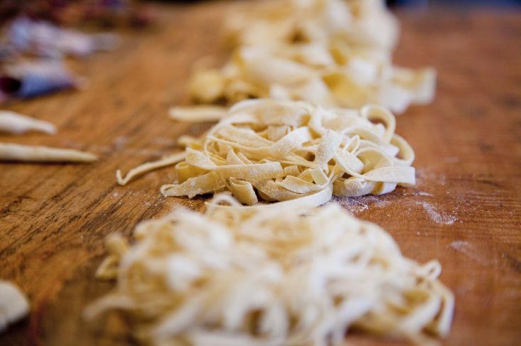 Una dettagliata immagine di fettuccine fresche su un tavolo di legno.