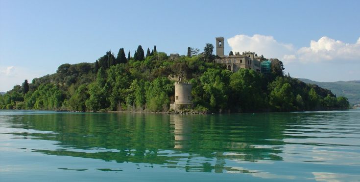 Isola tranquilla con un palazzo immerso nella vegetazione verde attorno a un lago.