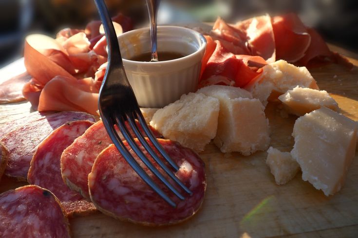 Un assortimento vario di salumi e formaggi servito su un tagliere di legno.