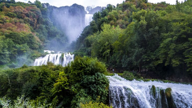 Una cascata immersa nella vegetazione verde. Il suono dell'acqua che scorre crea un'atmosfera tranquilla.
