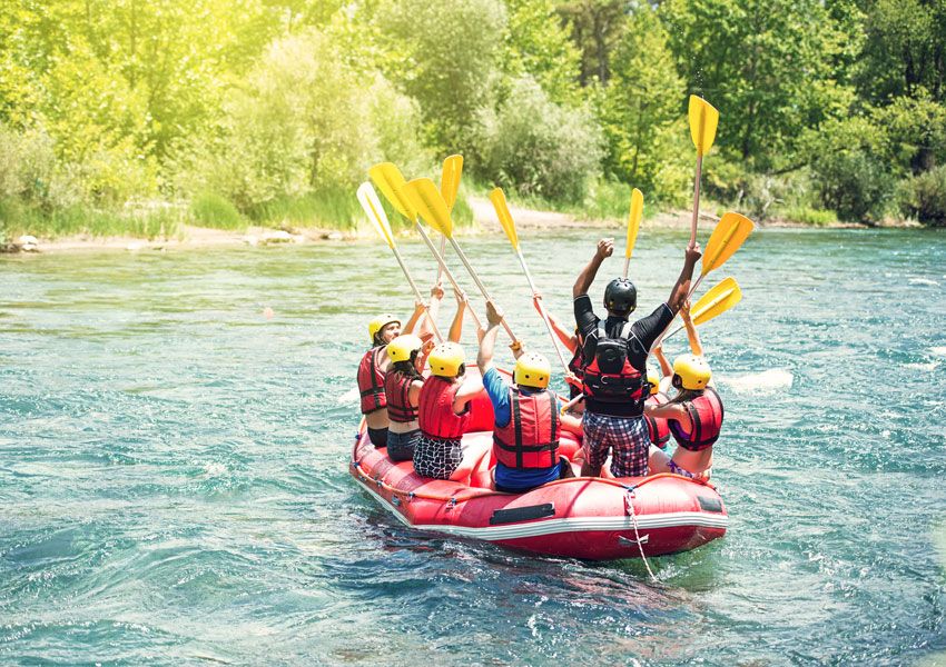 Un gruppo di persone partecipa a un'avventura di rafting sul fiume, immersi nella natura circostante.