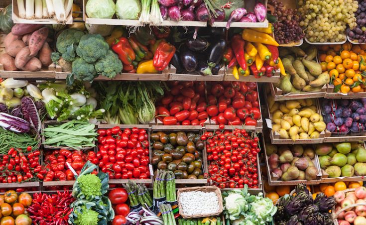 Scelta variegata di frutta e verdura fresca in un mercato affollato.