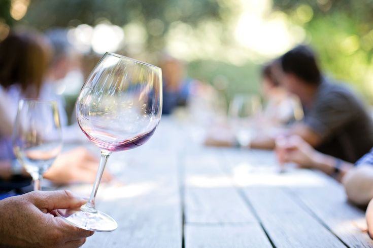 Un bicchiere di vino rosso servito all'aperto, circondato da un'atmosfera calda e accogliente.