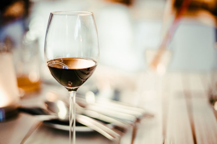 Un bicchiere di vino rosso su un tavolo semplice, pronto per una cena tranquilla.