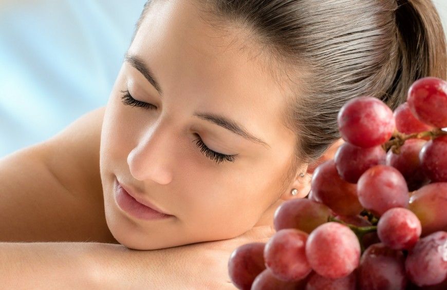 Una giovane donna si riposa accanto ad un grappolo d'uva, simbolo di relax e gusto. 
