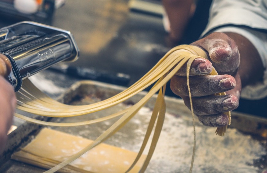 Una persona prepara la pasta fresca, la tradizione culinaria italiana in un momento di lavorazione.