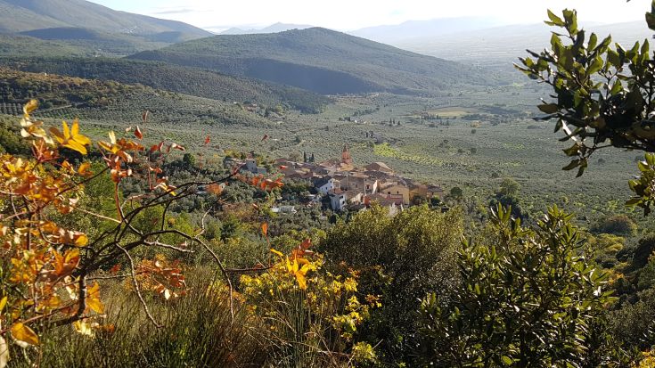 Un panorama di un borgo circondato da colline e vegetazione, tipico della stagione autunnale.