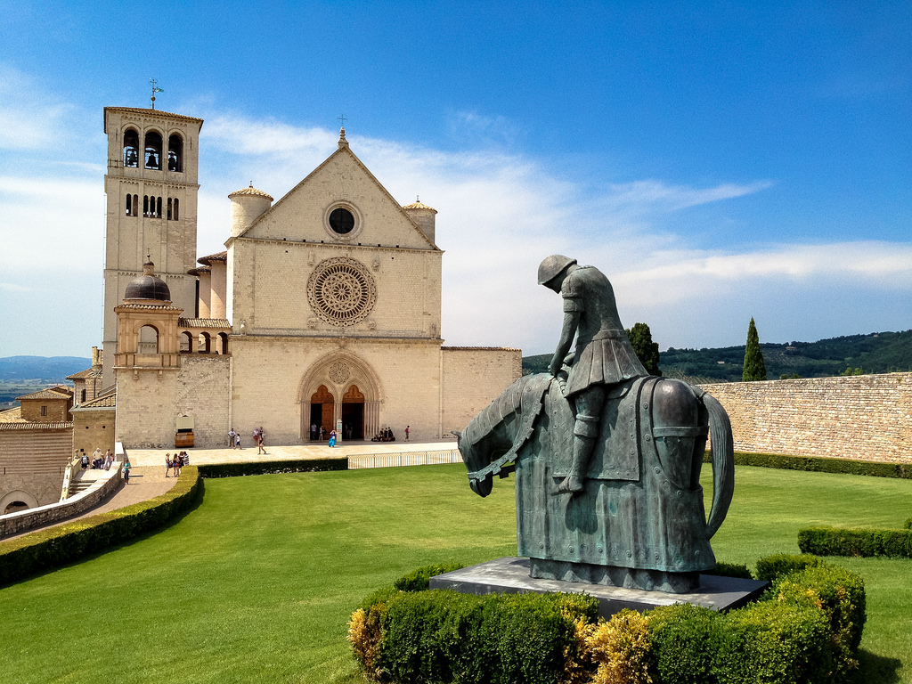 La Basilica di San Francesco a Assisi, con una scultura di cavaliere nel giardino antistante.