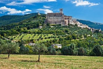 Scena di Assisi con le sue colline verdi e il monastero.