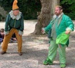 Due personaggi in abbigliamento folkloristico si esibiscono in un contesto naturale.
