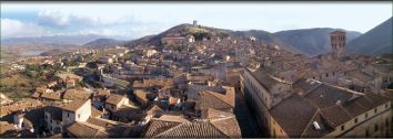 Un panorama di un antico borgo, immerso nel verde delle colline circostanti con case di pietra.