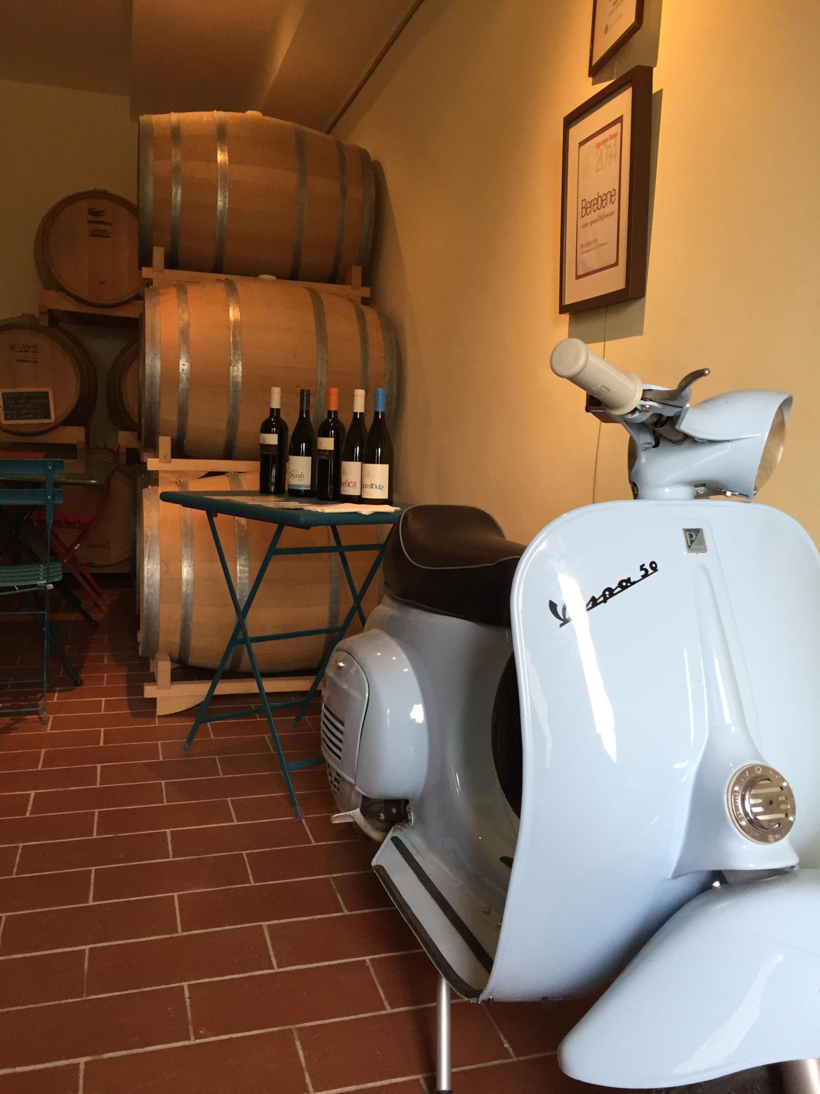 Un angolo caratteristico con una Vespa d'epoca e barili di vino, che rappresentano una tipica esperienza italiana.