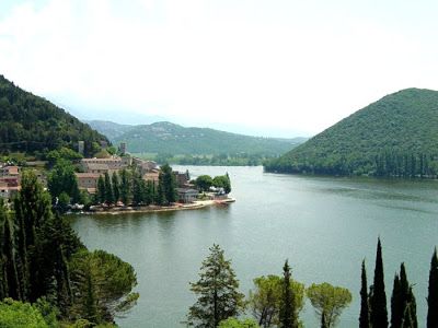 Un paesaggio tranquillo con un lago circondato da colline verdi e alberi, ideale per trascorrere del tempo all'aperto.