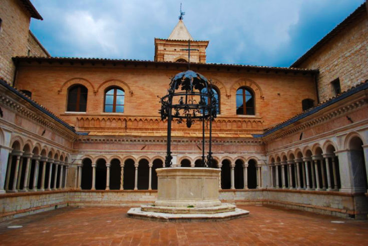 Un chiostro ben conservato con un pozzo centrale, circondato da archi e dettagli architettonici semplici.