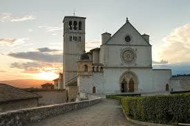 La Basilica di San Francesco a Assisi illuminata da un tranquillo tramonto.