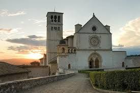 La Basilica di San Francesco a Assisi illuminata da un tranquillo tramonto.