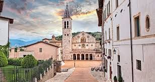 Un'area tranquilla con una chiesa e un campanile, circondata da edifici storici.