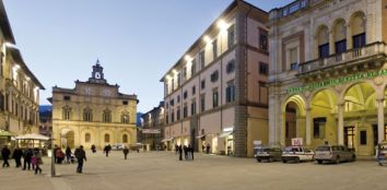 Una scena serale della piazza, caratterizzata da architetture storiche e un'atmosfera tranquilla.