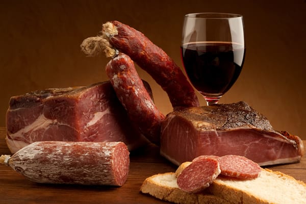 Selezione di salumi e un bicchiere di vino rosso.