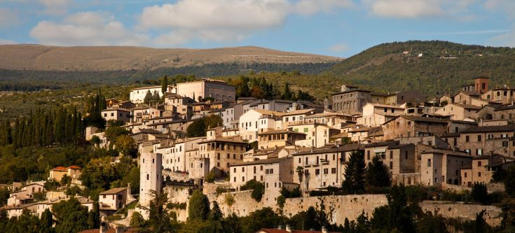 Un panorama di un borgo medievale circondato da colline verdi.