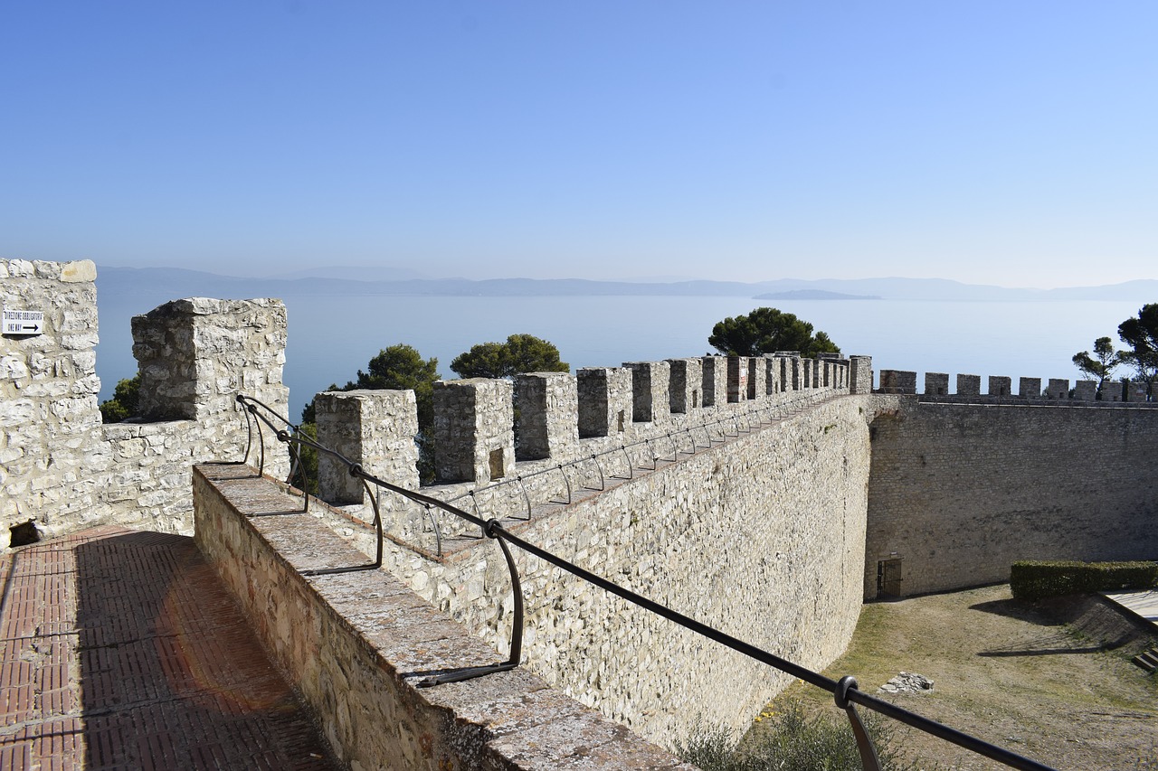 Un camminamento della cinta muraria interna della  Rocca del Leone a Castiglione del Lago, con il lago sullo sfondo in una giornata di sole.