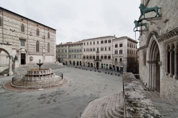 Una scena della Piazza IV Novembre, con la fontana e l'architettura storica circostante.