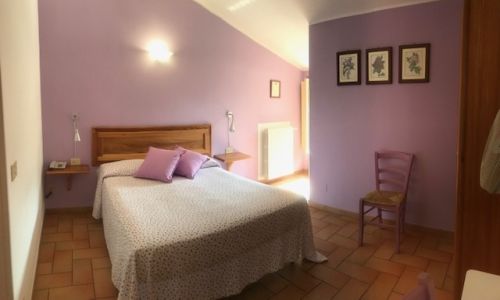 Camera luminosa con tonalità violette, adatta per momenti di relax e quiete. Arredo sobrio e confortevole.