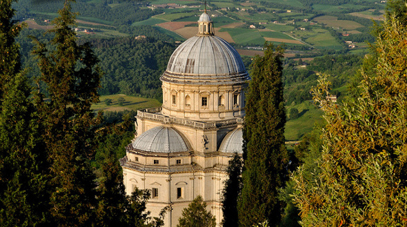 Chiesa situata tra alberi, circondata da un tranquillo paesaggio collinare.