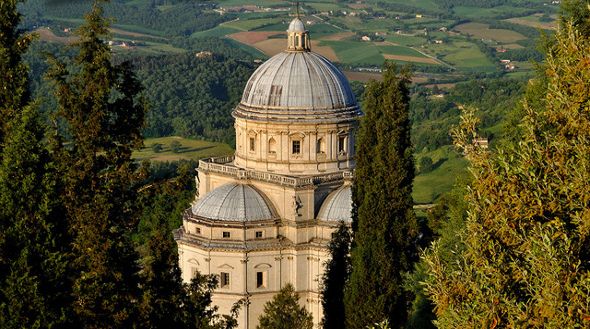 Chiesa situata tra alberi, circondata da un tranquillo paesaggio collinare.