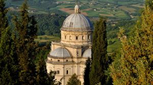 Chiesa situata tra alberi, circondata da un tranquillo paesaggio collinare.