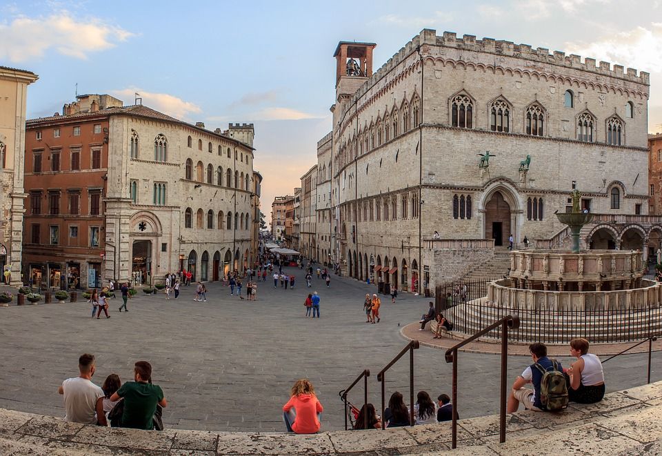 Piazza IV Novembre a Perugia, con palazzi storici e una fontana, frequentata da visitatori e residenti.