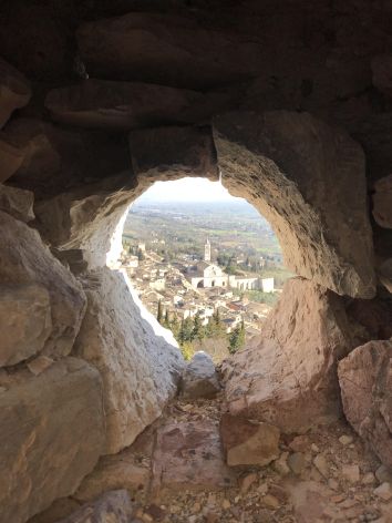 Attraverso un'apertura tra le rocce, si apre un paesaggio collinare e un centro storico che rappresenta la tradizione.