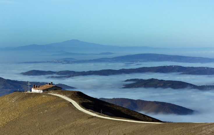 Panorama montano con nebbia. Un palazzo solitario si trova in cima a una collina.