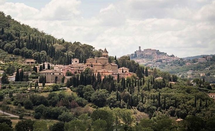 Un tranquillo paesaggio umbro con un borgo situato tra dolci colline e vegetazione verde.