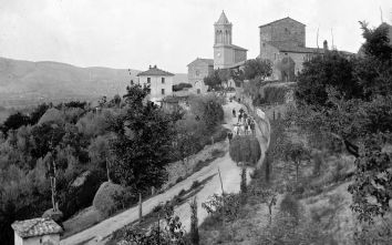 Un villaggio antico circondato da colline, con una chiesa e strade in pietra. Luogo caratteristico e tranquillo.