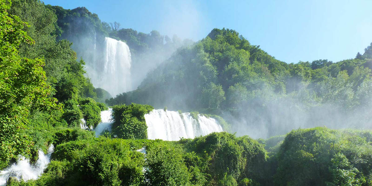 Cascata delle Marmore circondata da vegetazione lussureggiante in un ambiente naturale.