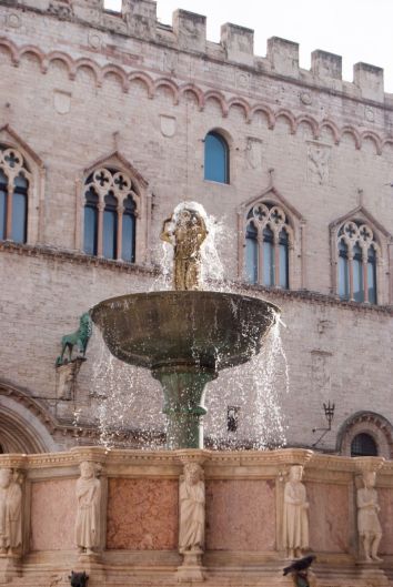 Una fontana storica con figure decorative, inserita in un contesto architettonico di interesse.