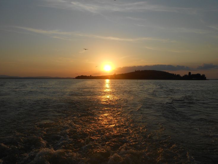 Un tranquillo tramonto si riflette sulle acque serene del lago, creando un'atmosfera suggestiva.