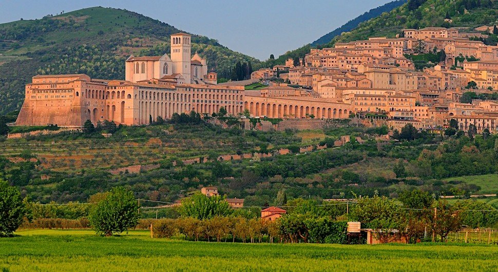 Basilica di Assisi , situata tra colline verdi e campi coltivati, creando un paesaggio suggestivo.