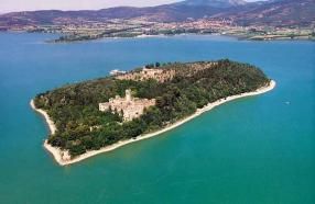 Isola tranquilla e verde con rovine storiche, circondata da acque tranquille.