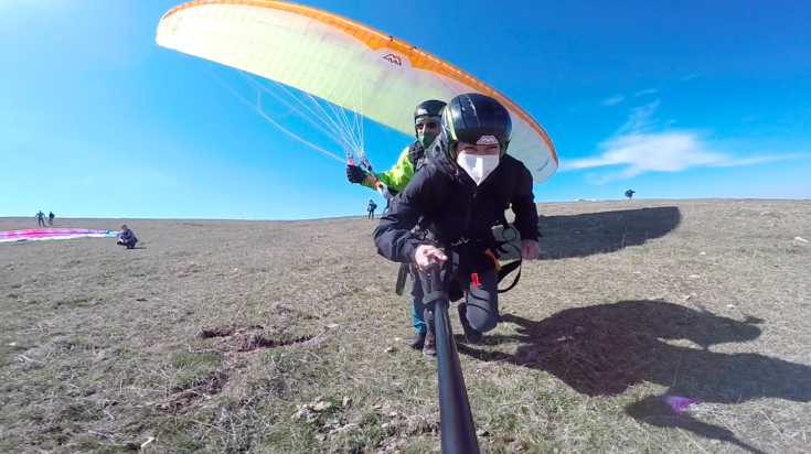 Un'azione di parapendio in un paesaggio naturale, caratterizzato da ampie aree verdi e un cielo limpido.