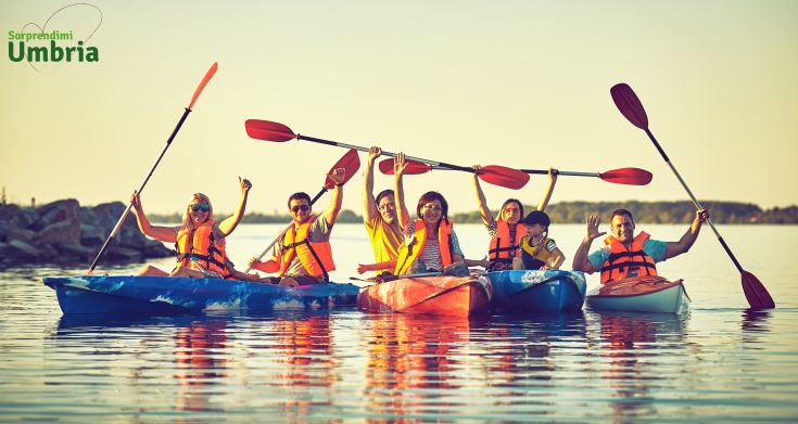Un gruppo di amici in kayak su un lago al tramonto, in un'atmosfera serena e conviviale.