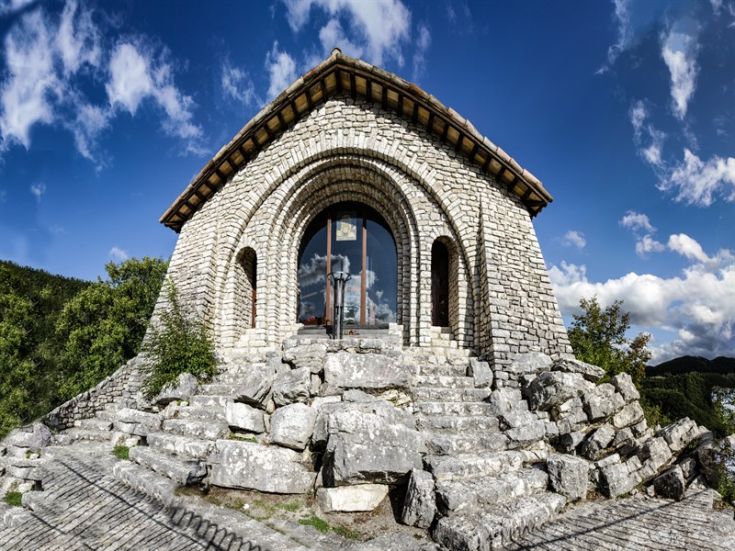 Un santuario semplice situato sulla collina di Cascia, circondata da vegetazione verde.