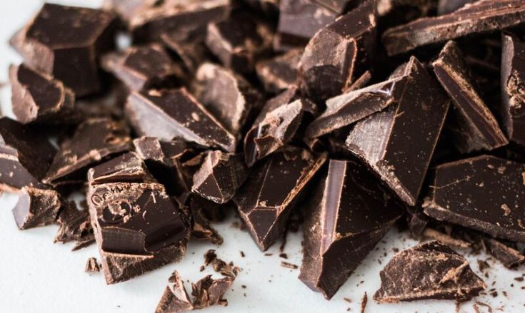 Pezzi di cioccolato fondente disposti su un tavolo, pronti per essere utilizzati in dolci o per essere assaporati.