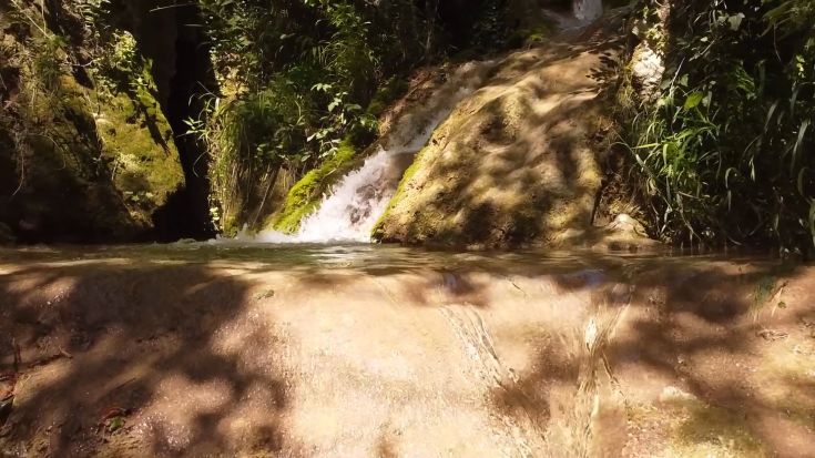 Una cascata tranquilla immersa in un ambiente verdeggiante, rappresentante la semplicità della natura.