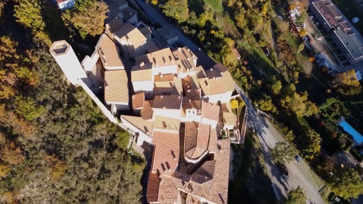 Scena di un grazioso borgo con tetti in terracotta, circondato dalla natura e che riflette tradizioni locali.