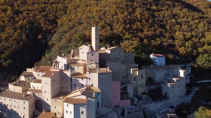Un antico borgo circondato dalla natura, con case storiche e una torre che si erge sul panorama.