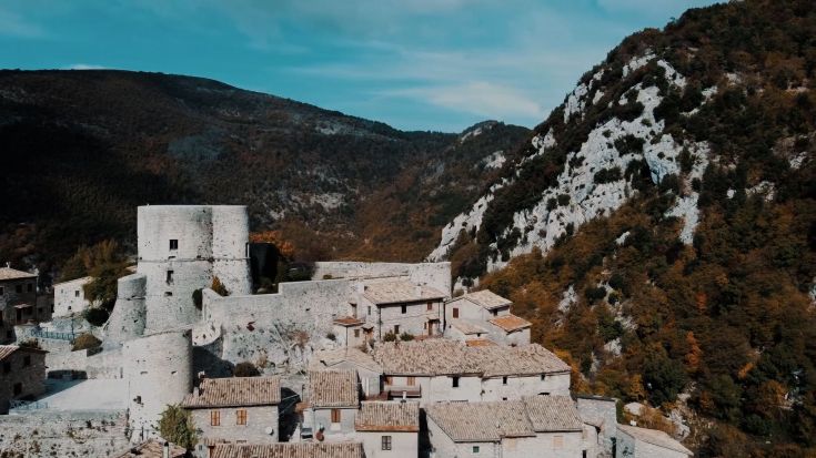 Borgo medievale incastonato tra le montagne, caratterizzato da architettura storica e atmosfera tranquilla.