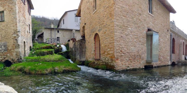 Un angolo tranquillo di un antico borgo con case in pietra e un ruscello che scorre dolcemente.