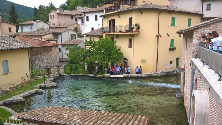 Un tranquillo angolo di un borgo storico con edifici tradizionali e un caratteristico specchio d'acqua, ideale per passeggiate.